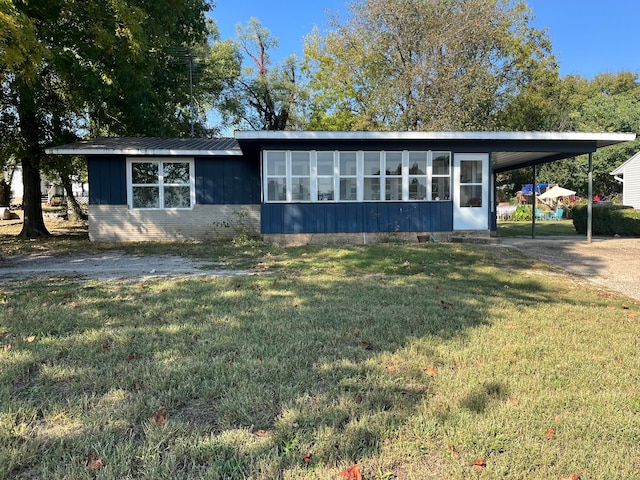 ranch-style house with a front lawn, a sunroom, and a carport