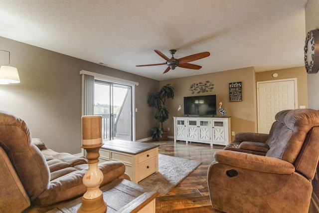 living room with a textured ceiling, ceiling fan, and dark hardwood / wood-style flooring