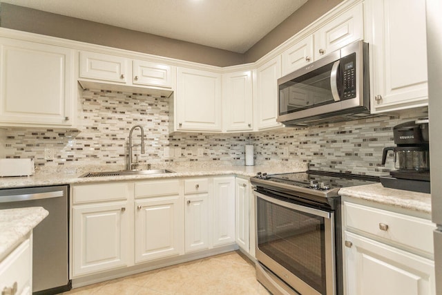 kitchen with tasteful backsplash, appliances with stainless steel finishes, sink, and white cabinetry