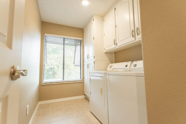 laundry room with a textured ceiling, washing machine and clothes dryer, light tile patterned floors, and cabinets