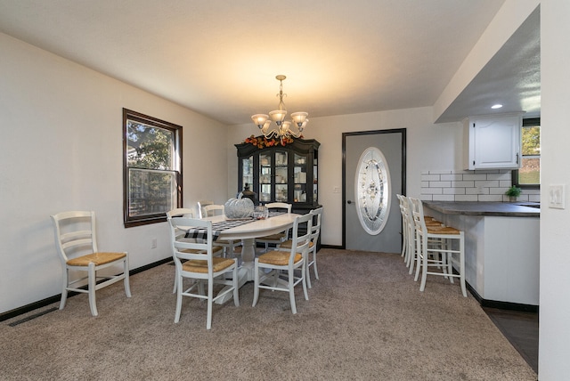 dining area with dark colored carpet and a chandelier