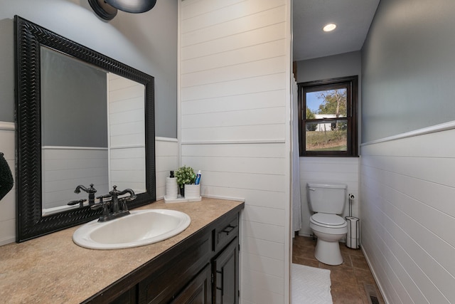 bathroom featuring tile patterned floors, vanity, tile walls, and toilet