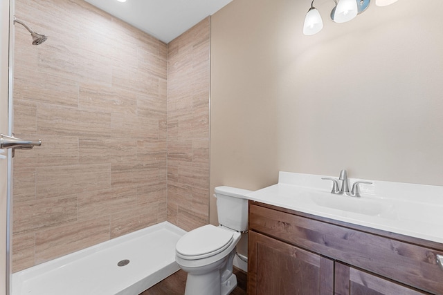 bathroom with a tile shower, vanity, and toilet