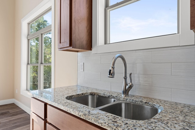 kitchen with light stone countertops, dark wood-type flooring, sink, and tasteful backsplash