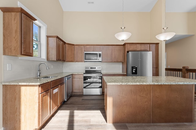 kitchen featuring tasteful backsplash, sink, stainless steel appliances, hanging light fixtures, and hardwood / wood-style flooring