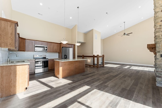 kitchen with stainless steel appliances, pendant lighting, high vaulted ceiling, and a kitchen island