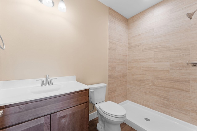 bathroom featuring a tile shower, vanity, and toilet