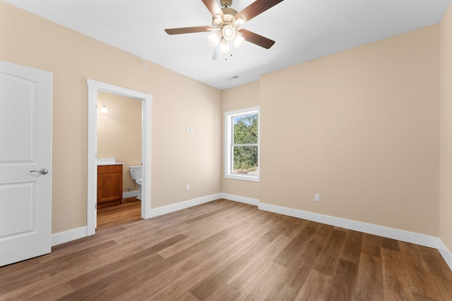 unfurnished bedroom with ensuite bathroom, hardwood / wood-style flooring, and ceiling fan