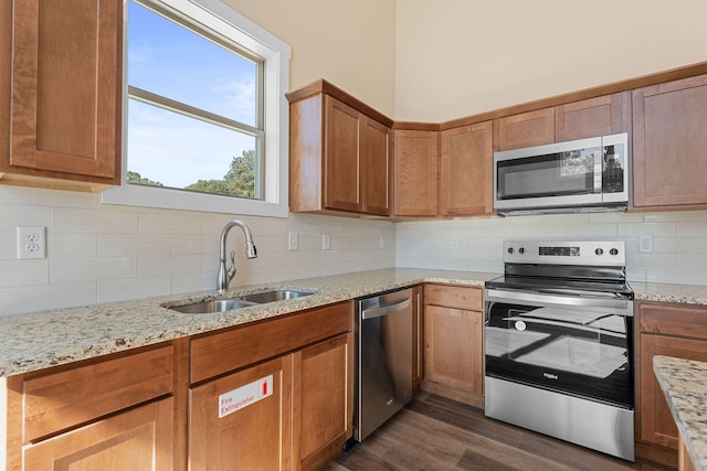 kitchen featuring light stone countertops, decorative backsplash, sink, dark hardwood / wood-style flooring, and appliances with stainless steel finishes