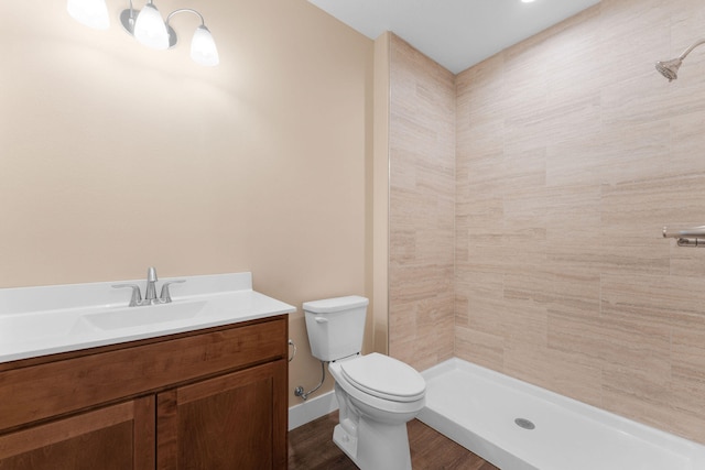 bathroom with a tile shower, vanity, toilet, and hardwood / wood-style flooring