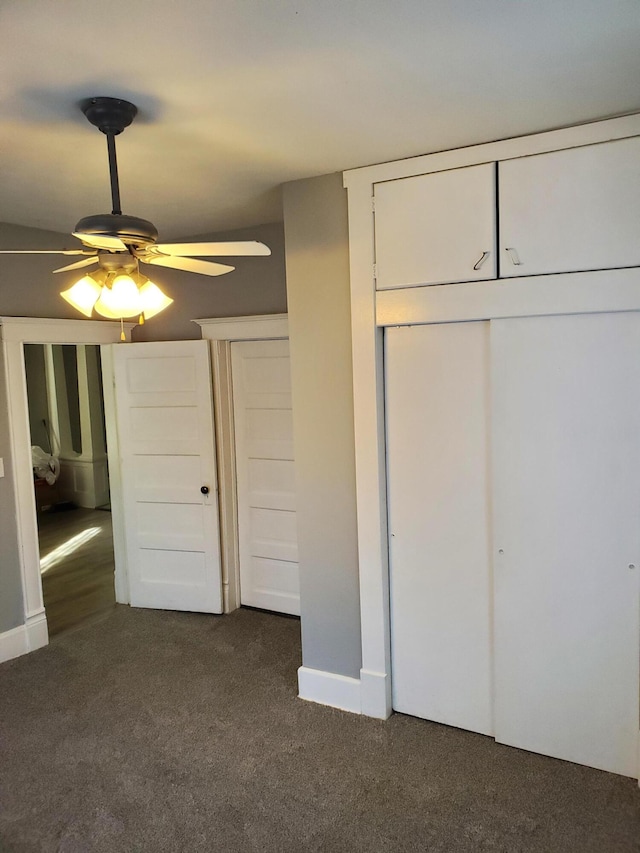 unfurnished bedroom with ceiling fan and dark colored carpet