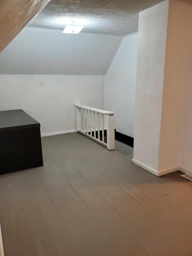 bonus room with vaulted ceiling, wood-type flooring, and a textured ceiling