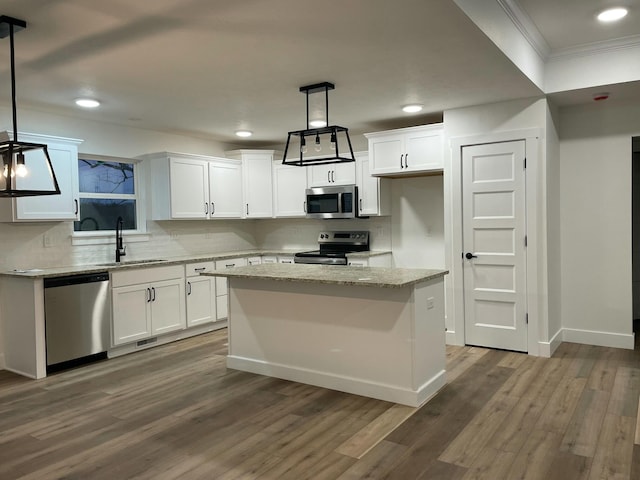 kitchen with white cabinets, decorative light fixtures, a center island, and appliances with stainless steel finishes