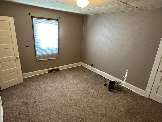 carpeted empty room with wooden walls