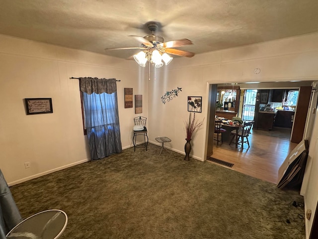 interior space with dark colored carpet, a textured ceiling, and ceiling fan