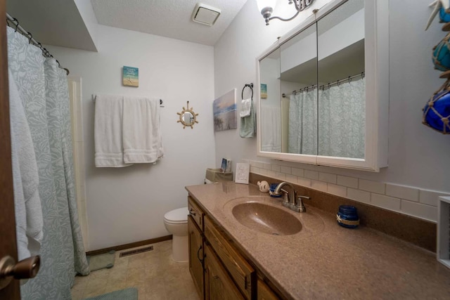 bathroom with tile patterned flooring, toilet, tasteful backsplash, vanity, and a textured ceiling