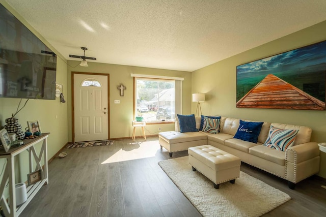 living room featuring ceiling fan, a textured ceiling, and dark hardwood / wood-style floors