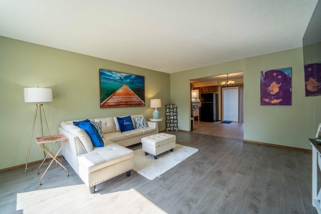 living room with wood-type flooring, an inviting chandelier, and a textured ceiling