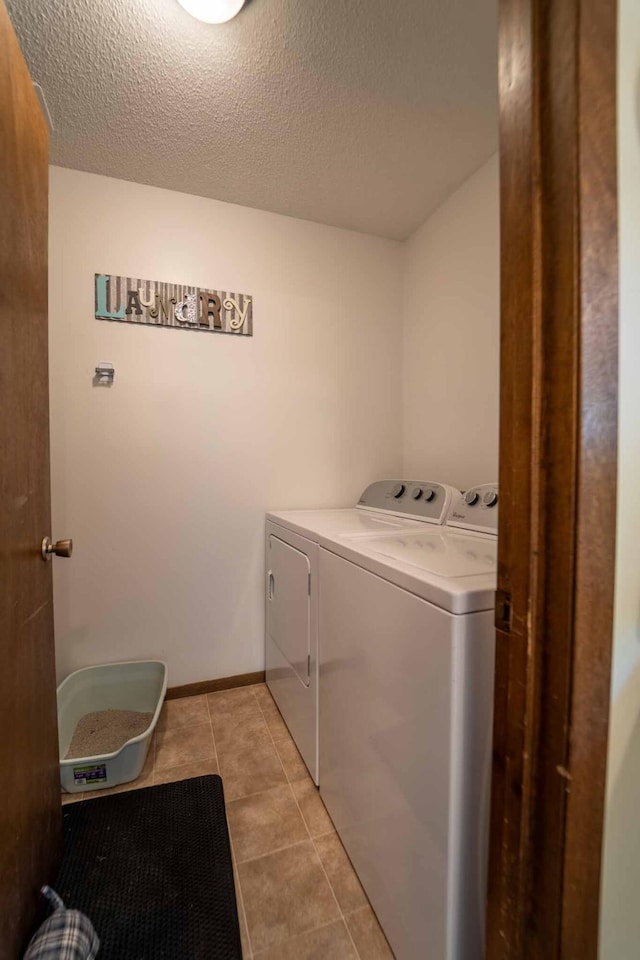 washroom featuring a textured ceiling, independent washer and dryer, and light tile patterned flooring