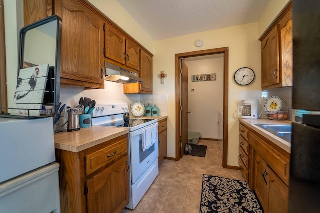 kitchen with sink, light tile patterned floors, white appliances, a textured ceiling, and decorative backsplash