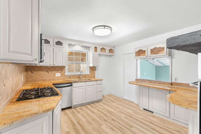 kitchen with light stone countertops, appliances with stainless steel finishes, sink, white cabinets, and light hardwood / wood-style flooring