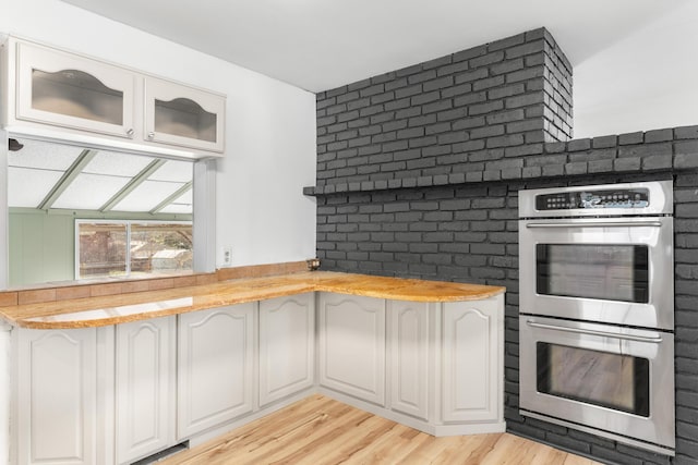 kitchen featuring white cabinets, light hardwood / wood-style flooring, and double oven