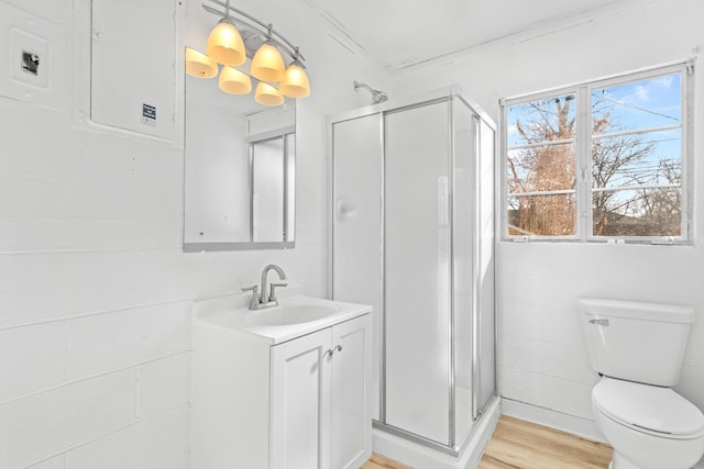 bathroom featuring wood-type flooring, a shower with door, toilet, and vanity