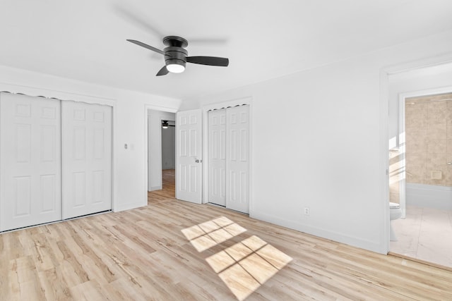 unfurnished bedroom featuring multiple closets, light hardwood / wood-style floors, connected bathroom, and ceiling fan