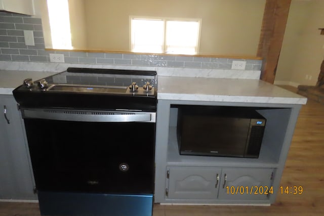 kitchen featuring backsplash, white cabinets, light hardwood / wood-style floors, and electric range