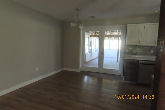 unfurnished dining area with dark wood-type flooring and an inviting chandelier