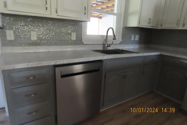 kitchen featuring sink, stainless steel dishwasher, backsplash, white cabinetry, and dark hardwood / wood-style floors