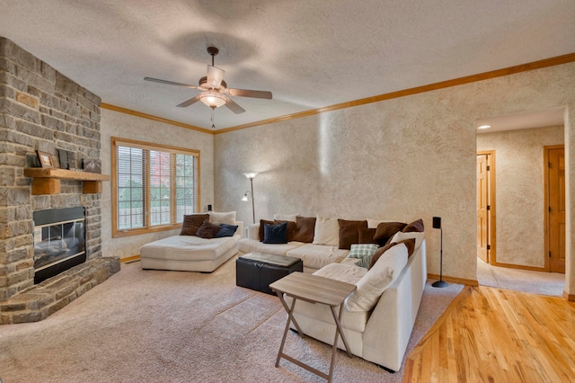 living room with ceiling fan, wood-type flooring, crown molding, a fireplace, and a textured ceiling