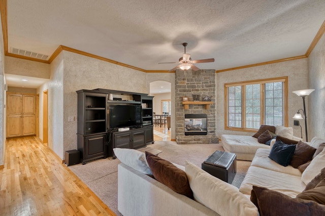 living room with ornamental molding, light wood-type flooring, ceiling fan, and a textured ceiling