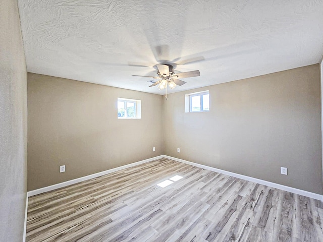 empty room featuring ceiling fan, a textured ceiling, and light hardwood / wood-style flooring