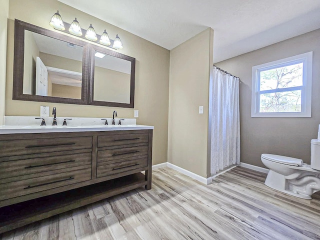 bathroom featuring hardwood / wood-style flooring, vanity, toilet, and curtained shower