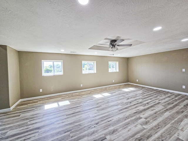 empty room featuring a textured ceiling, light wood-type flooring, and ceiling fan