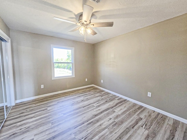 empty room with ceiling fan and light hardwood / wood-style floors