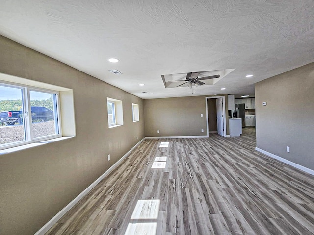 unfurnished living room featuring ceiling fan, a textured ceiling, and light hardwood / wood-style flooring