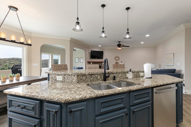 kitchen featuring light stone countertops, dark hardwood / wood-style floors, sink, crown molding, and a center island with sink