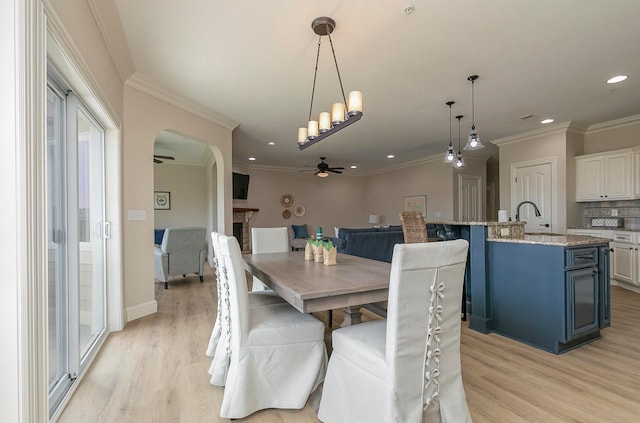 dining room with ceiling fan, sink, light hardwood / wood-style flooring, and ornamental molding