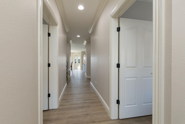 hallway featuring ornamental molding and light hardwood / wood-style flooring