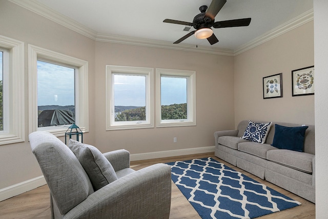 living room with ceiling fan, light hardwood / wood-style floors, ornamental molding, and a healthy amount of sunlight