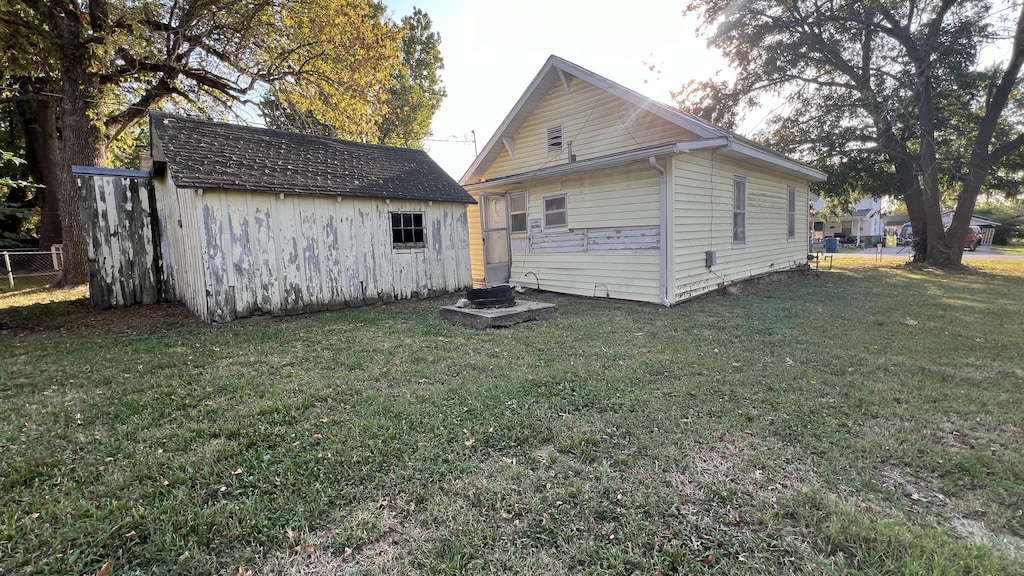 706 Walnut St, Lamar, MO 64759 - back of house with an outdoor structure, a yard, a shed, and fence