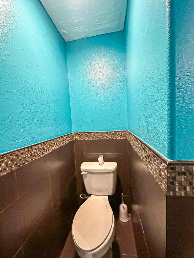 bathroom featuring tile walls and toilet