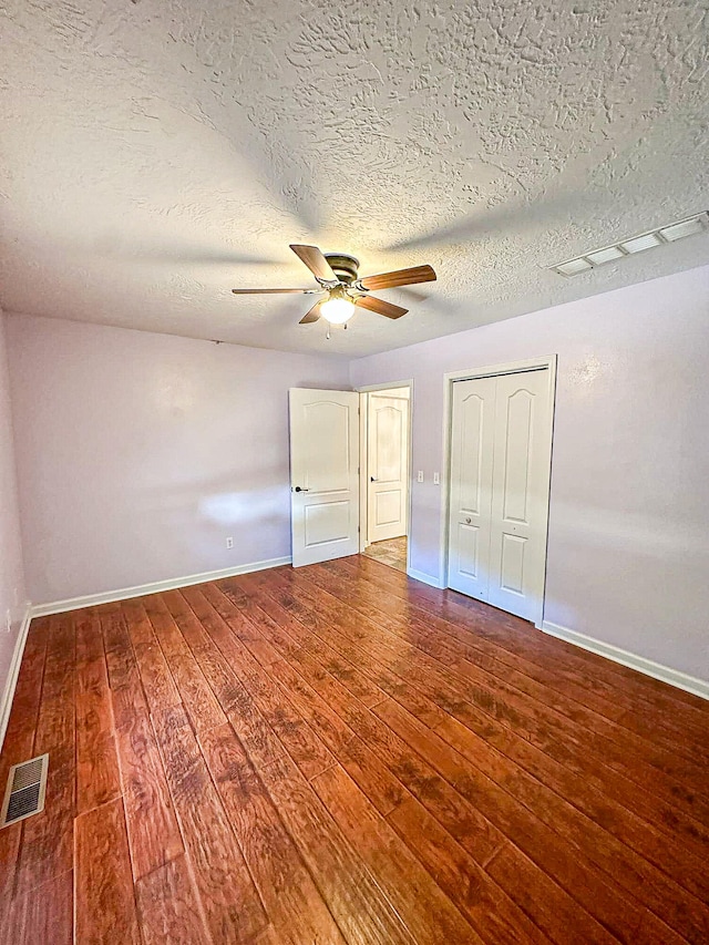 unfurnished bedroom with hardwood / wood-style flooring, ceiling fan, a closet, and a textured ceiling