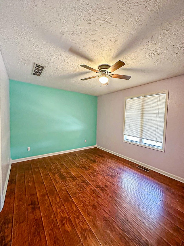 empty room with ceiling fan, dark hardwood / wood-style floors, and a textured ceiling