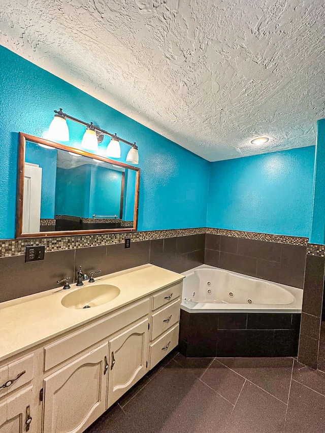 bathroom with tiled tub, vanity, tile patterned flooring, and a textured ceiling