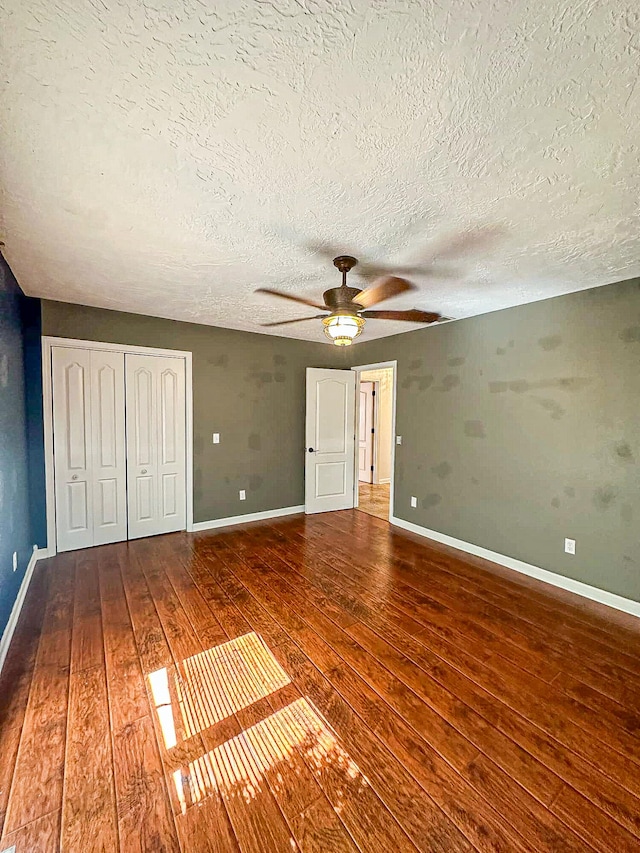 unfurnished bedroom featuring ceiling fan, hardwood / wood-style flooring, and a textured ceiling