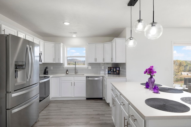 kitchen featuring white cabinets, stainless steel appliances, plenty of natural light, and sink