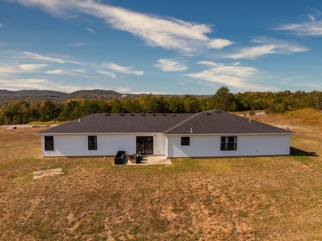 rear view of property with a yard, a mountain view, and a patio